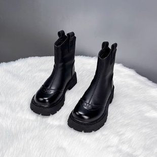 Schwarze Chelsea-Boots mit Plateausohle auf flauschigem Untergrund