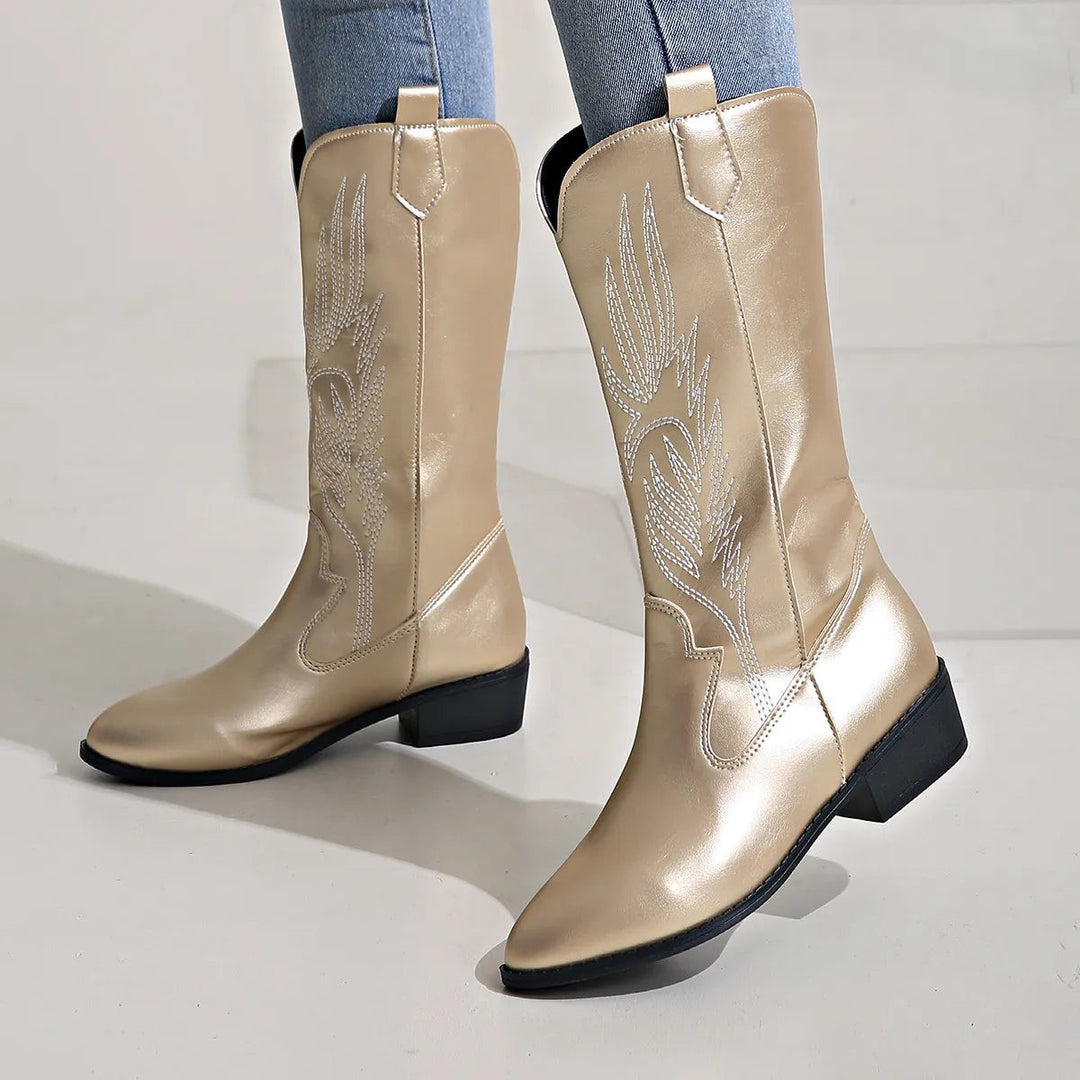 Goldfarbene Westernstiefel mit Stickmuster, Schrägansicht auf hellem Grund