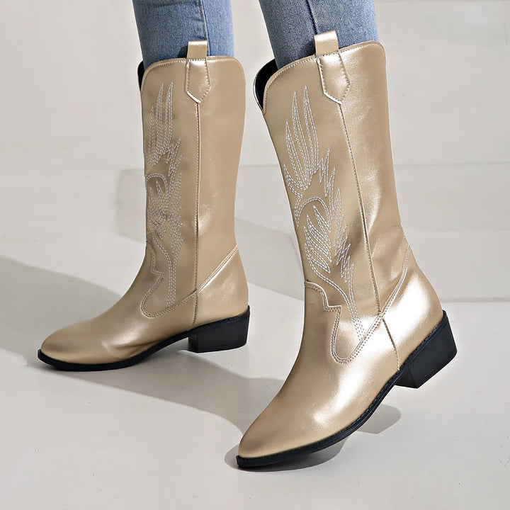 Goldfarbene Westernstiefel mit Stickmuster, Schrägansicht auf hellem Grund