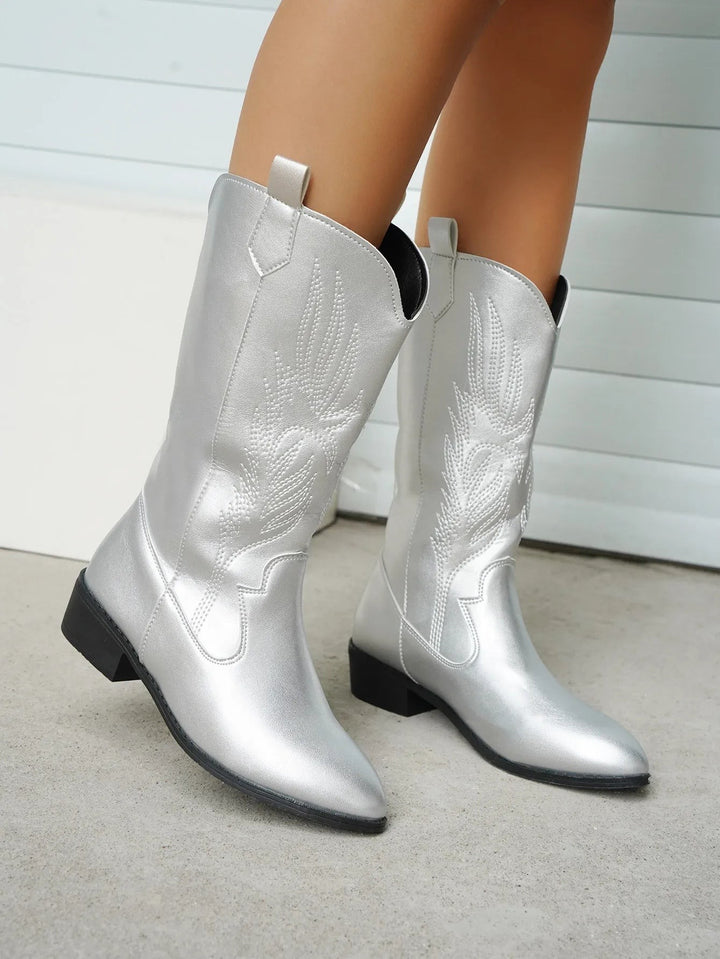 Silberne Cowboystiefel mit floraler Stickerei an schlanken Beinen