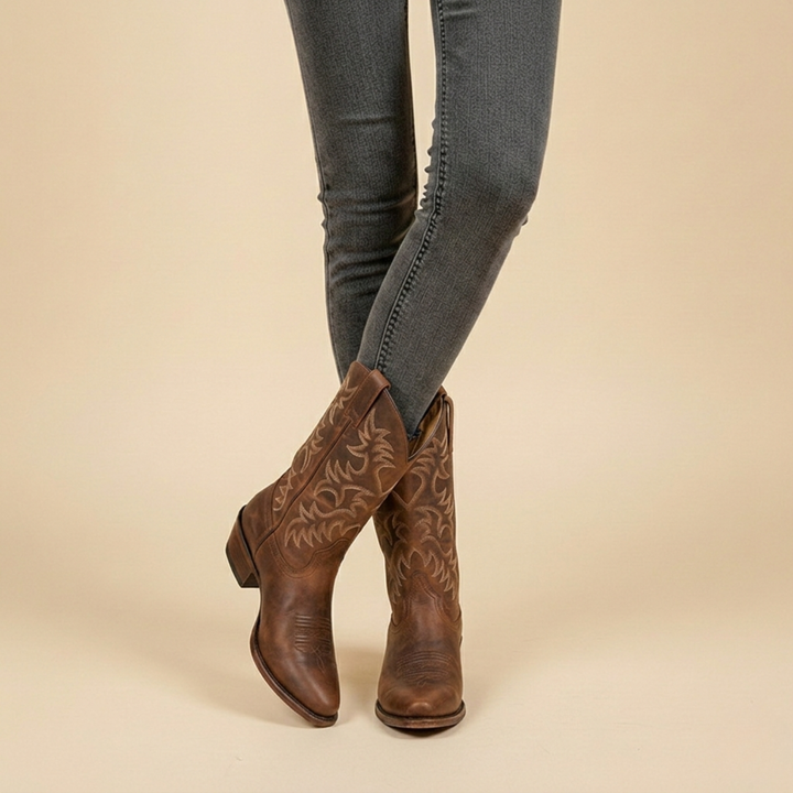 Braune Cowboystiefel aus Leder mit Stickmuster, getragen zu grauer Jeans