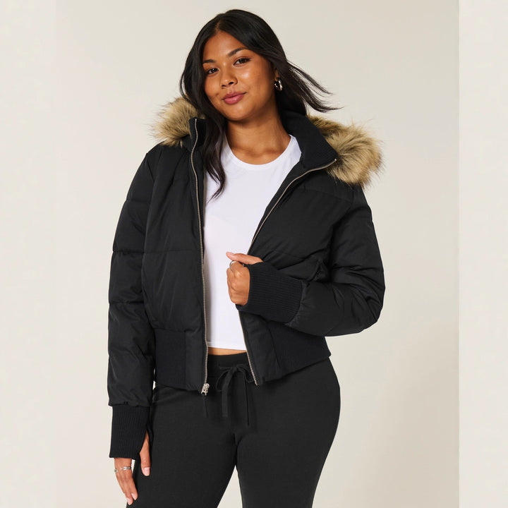 Schwarze Cropped Pufferjacke mit Kunstfellkapuze zu weißem T-Shirt getragen