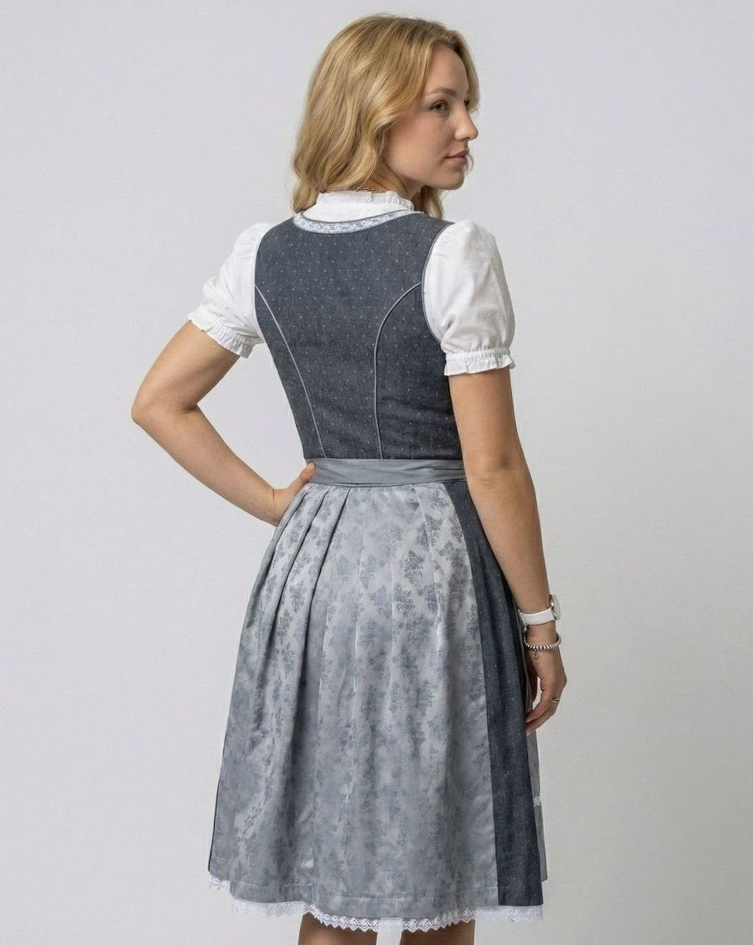 Rückansicht des grauen Dirndls mit geschnürter Taille und Faltenschürze