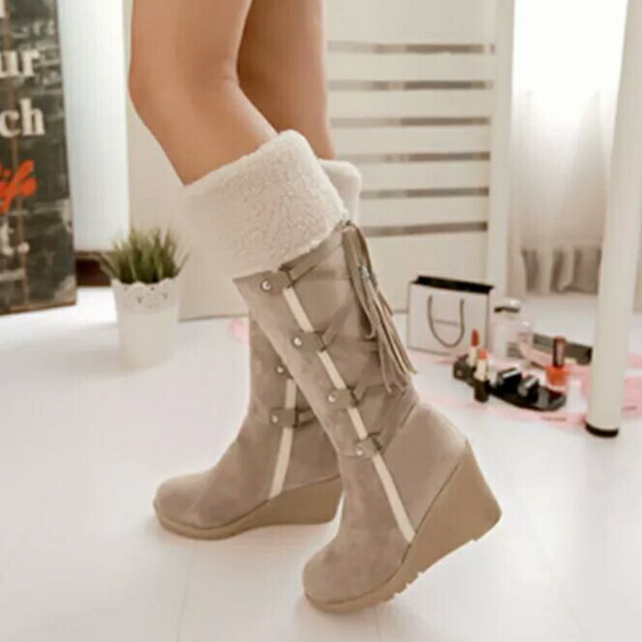 Beige Keilstiefel mit Fellumschlag und Fransenverzierung, am Fuß getragen