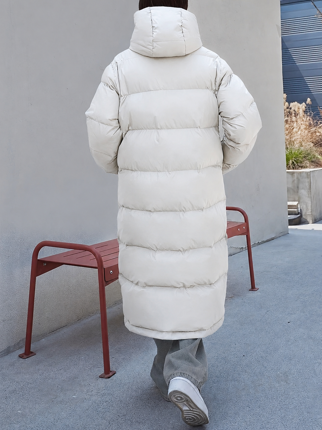 Rückansicht einer cremeweißen Daunenjacke mit Kapuze in maxi Länge