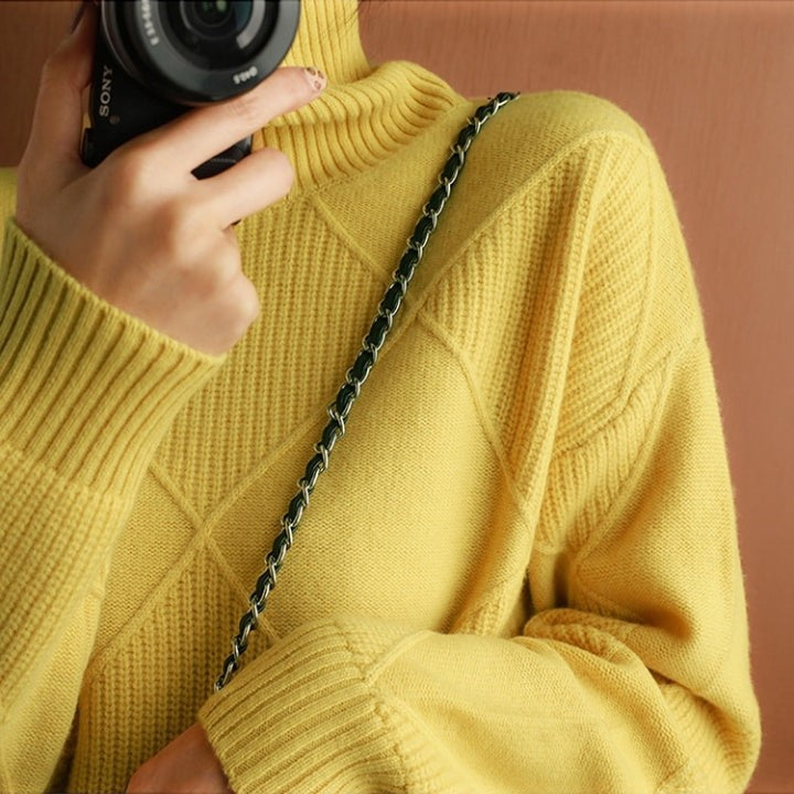 Nahaufnahme Rollkragenpullover gelb mit Kettenriemen der Tasche
