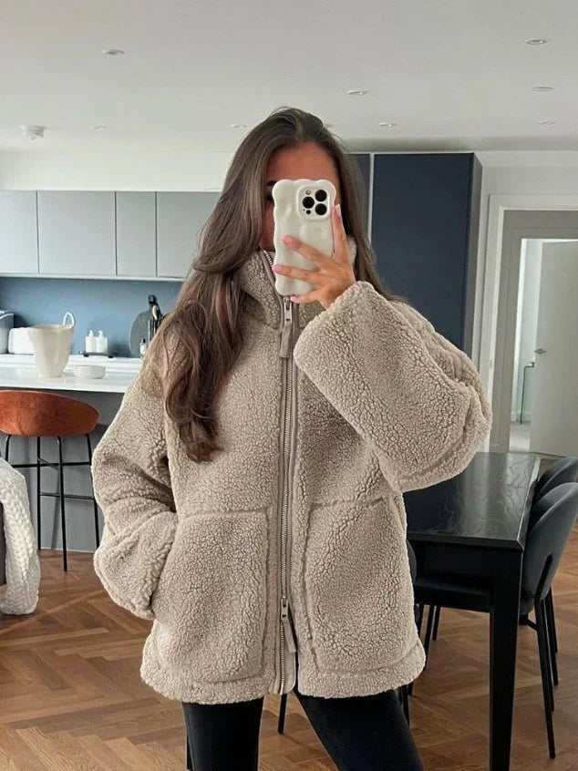 Frau trägt beige Oversized Teddyjacke mit Stehkragen im Wohnzimmer