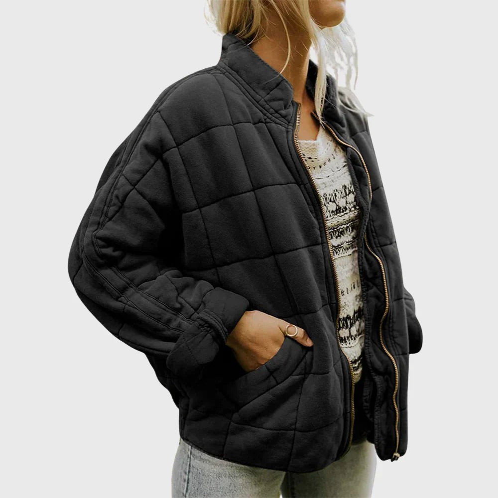 Schwarze gesteppte Jacke mit goldenem Reißverschluss, Hand in der Tasche