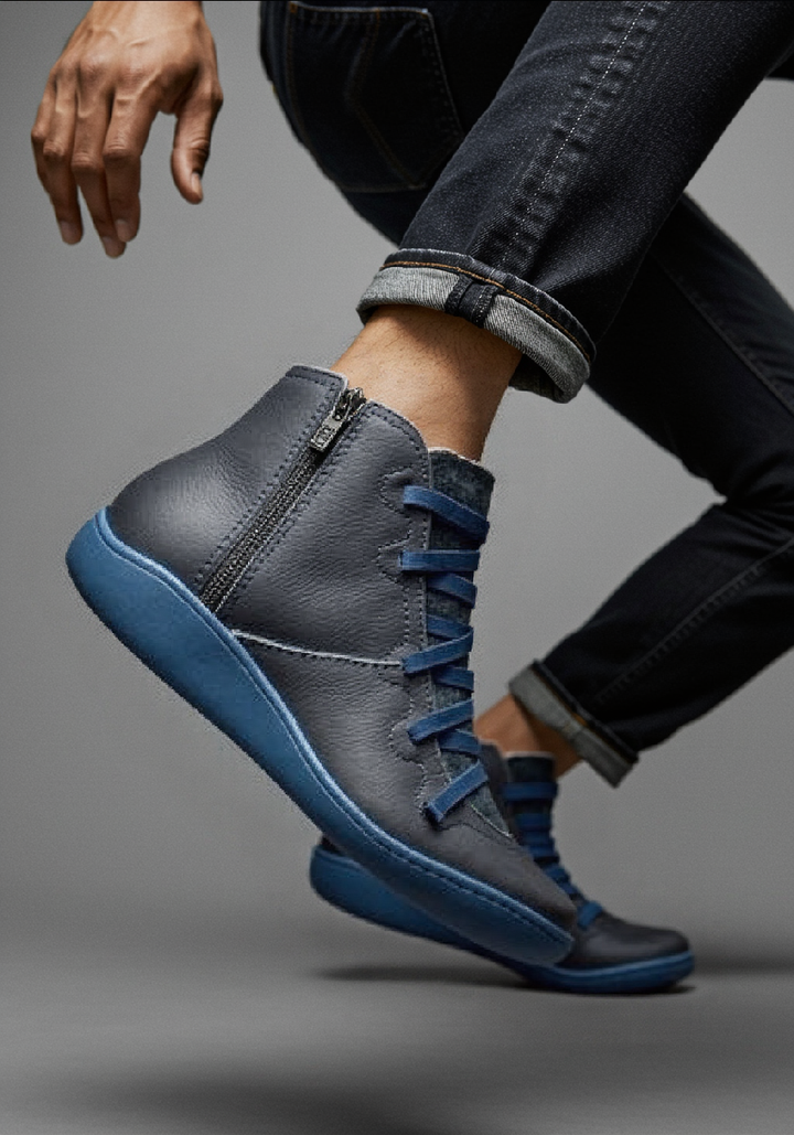 Graue Leder-Stiefelette mit blauer Sohle, am Fuß getragen mit Jeans
