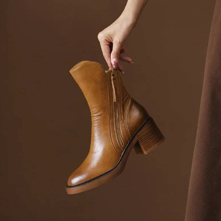 Cognacfarbener Ankle Boot aus Leder mit Blockabsatz in der Hand gehalten