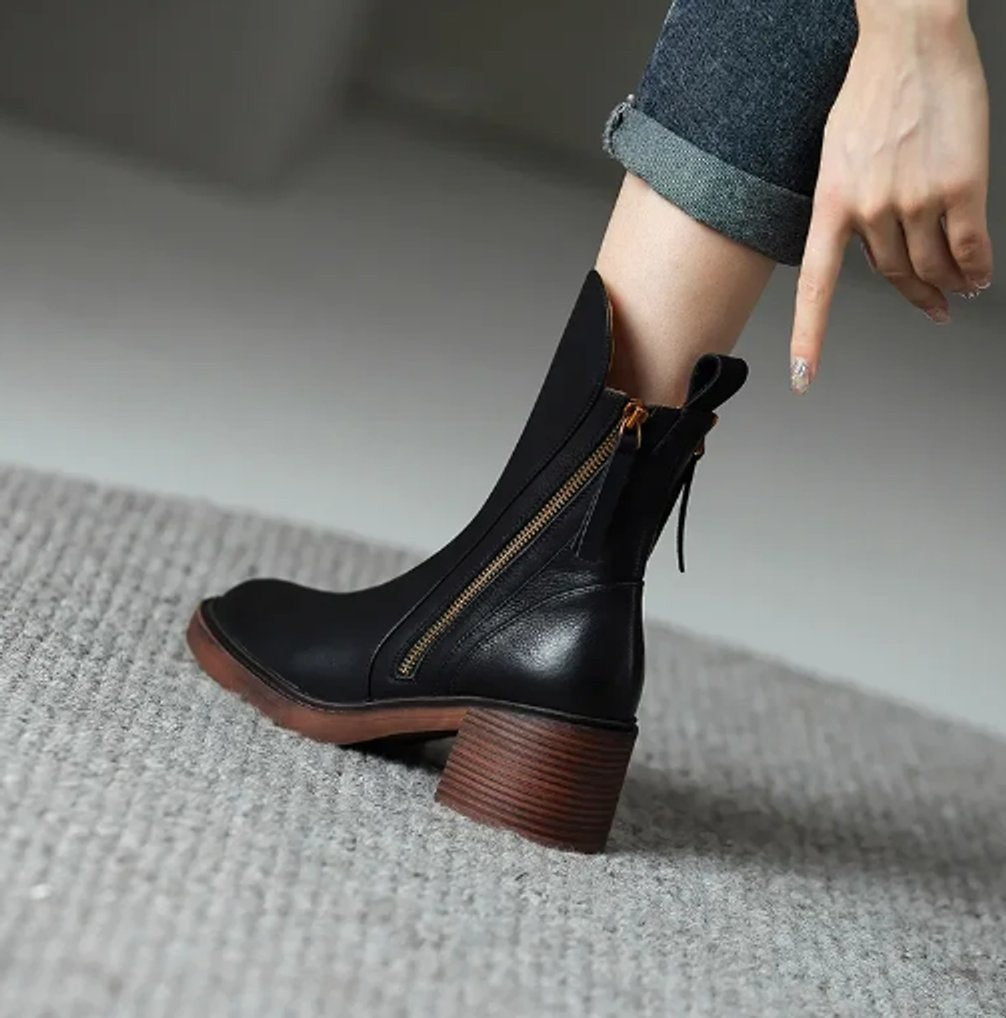 Schwarzer Ankle Boot aus Leder mit Blockabsatz am Fuß auf Teppich