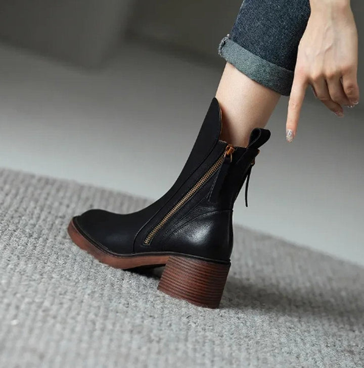 Schwarzer Ankle Boot aus Leder mit Blockabsatz am Fuß auf Teppich