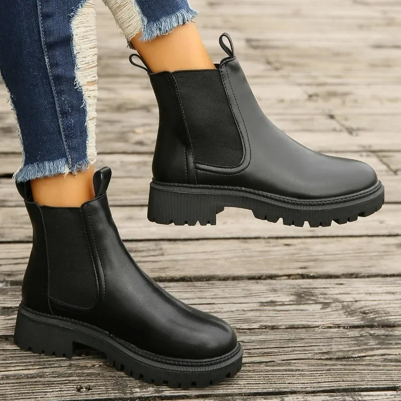 Schwarze Chelsea Boots aus Leder mit dicker Profilsohle getragen