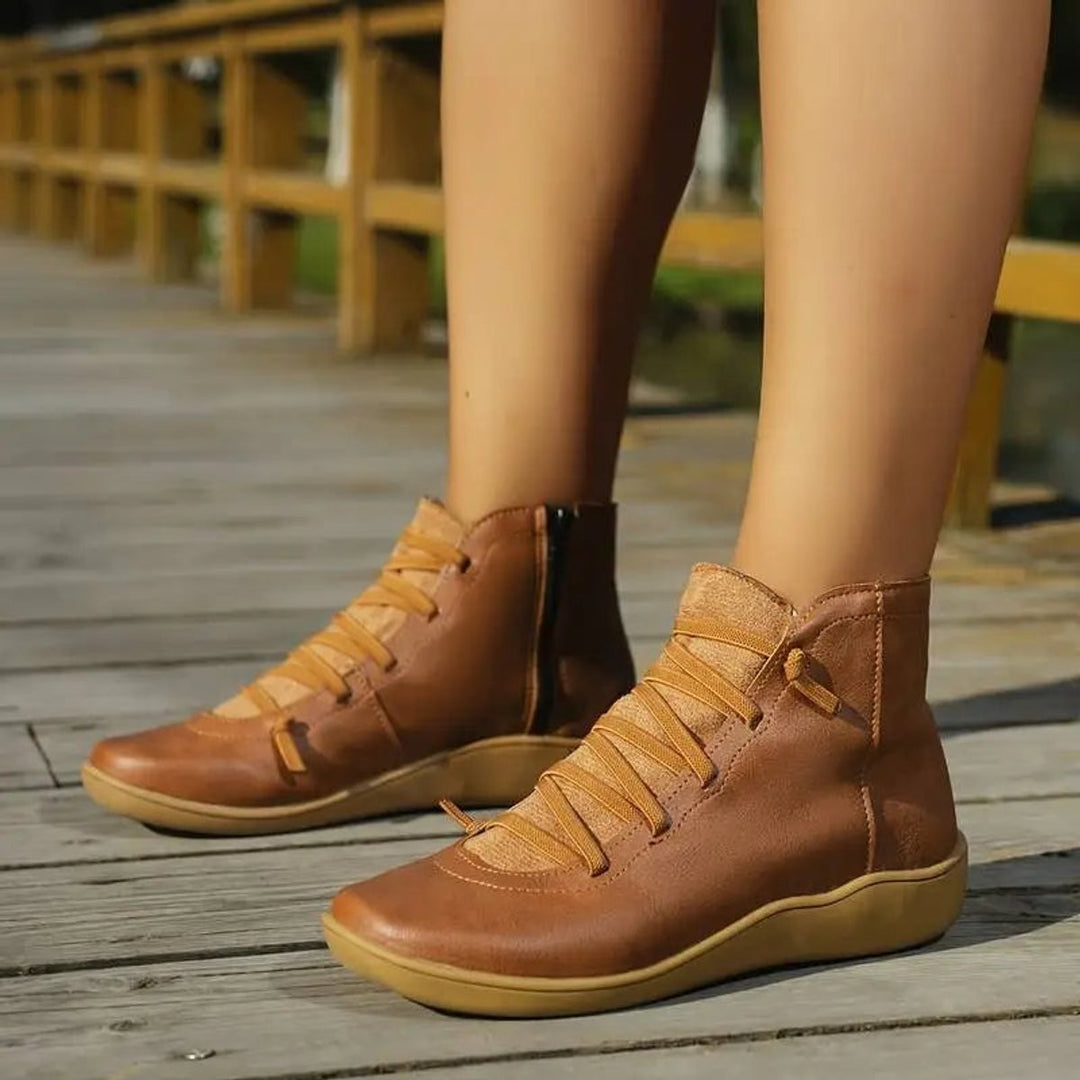 Cognacfarbene Ankle Boots am Fuß getragen auf Holzsteg