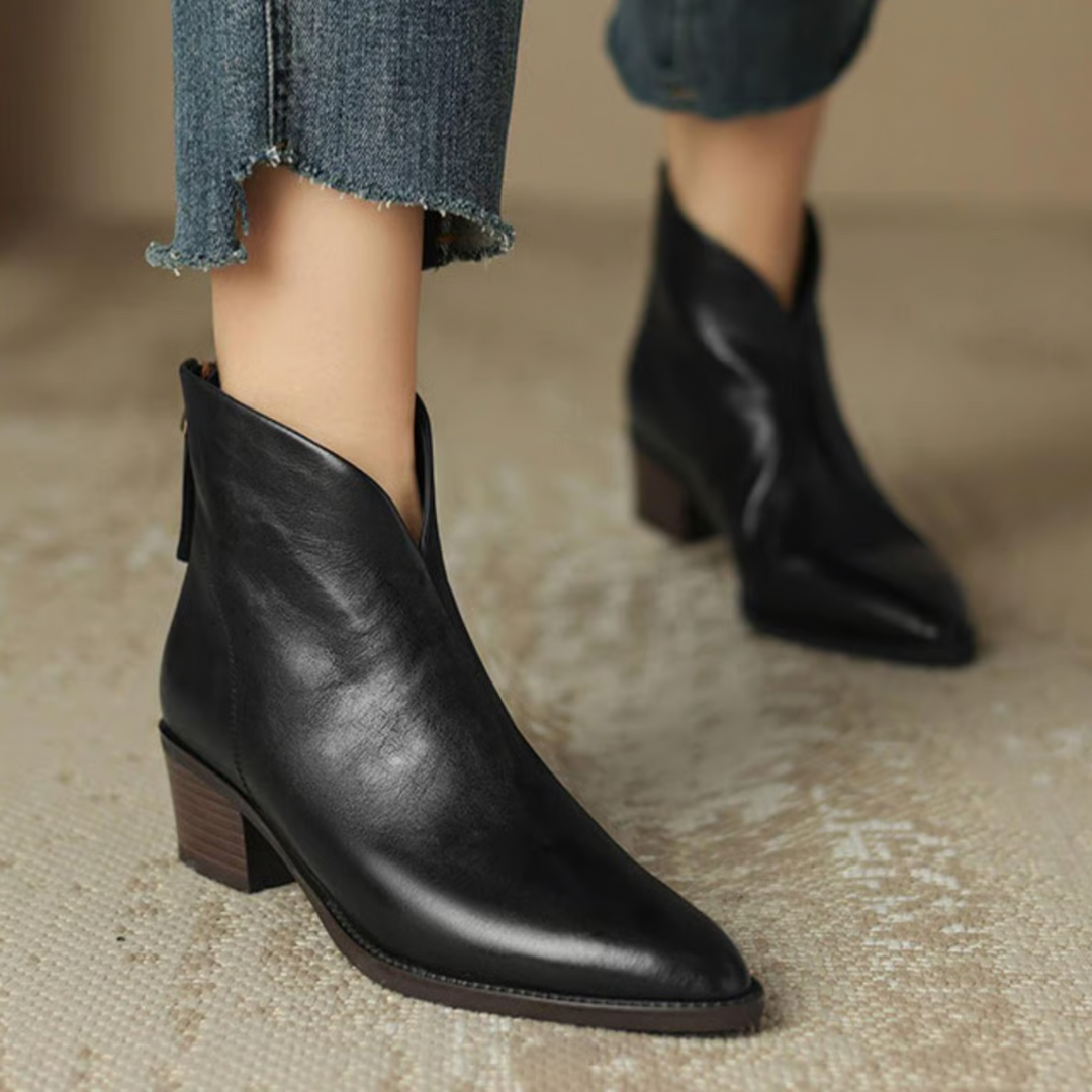 Schwarze Stiefeletten am Fuß getragen mit ausgefranster Jeans