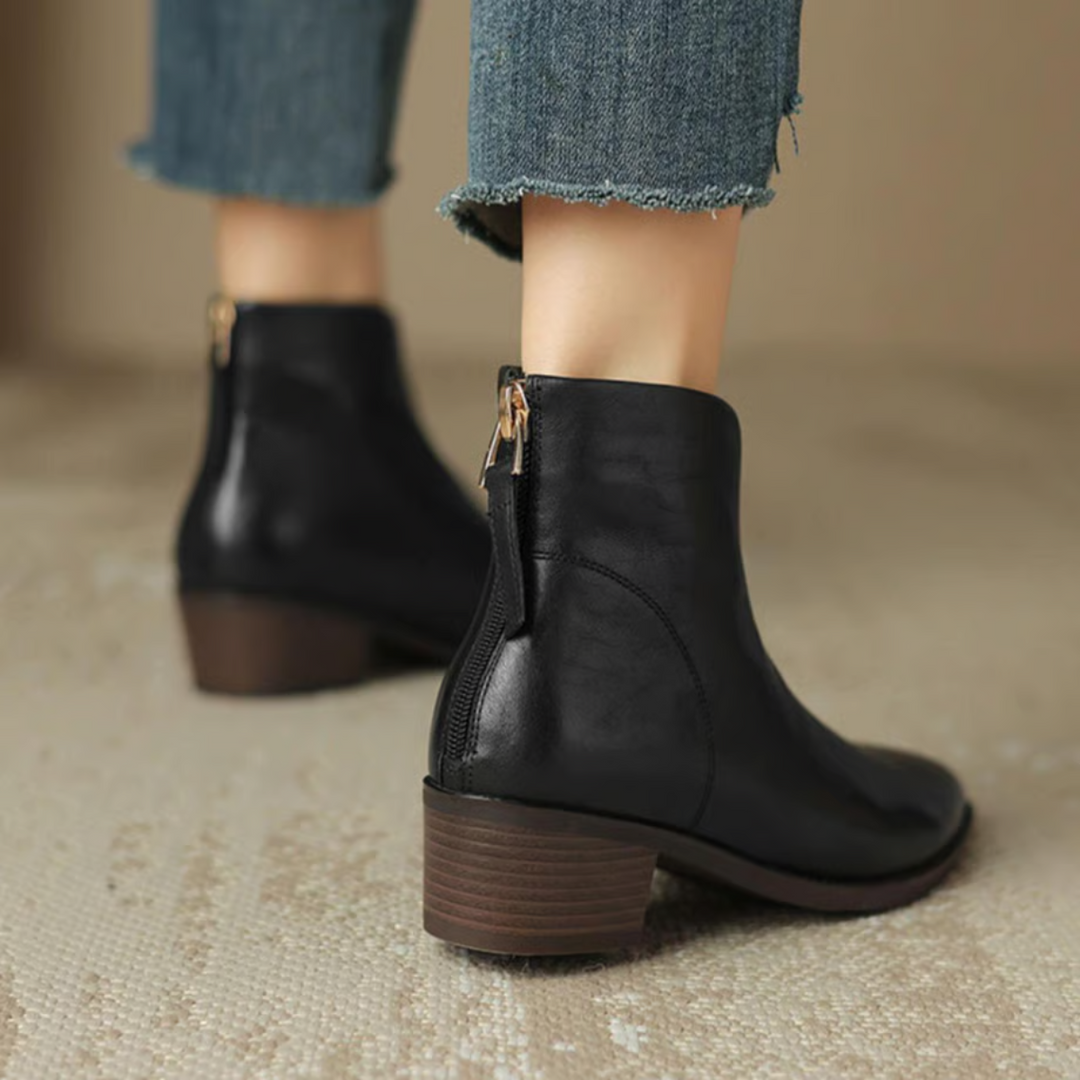 Schwarze Stiefeletten von hinten mit goldenem Reißverschluss am Fersenbereich