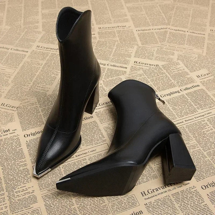 Schwarze Stiefeletten mit spitzer Kappe und Blockabsatz auf Zeitungsuntergrund