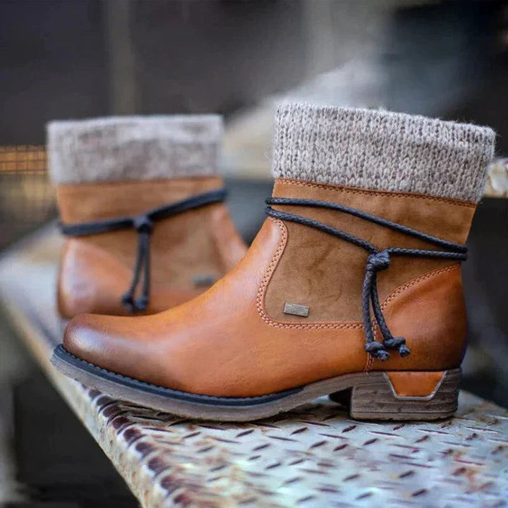 Cognacfarbene Lederstiefeletten mit Strickschaft, paarweise auf Holzbank drapiert