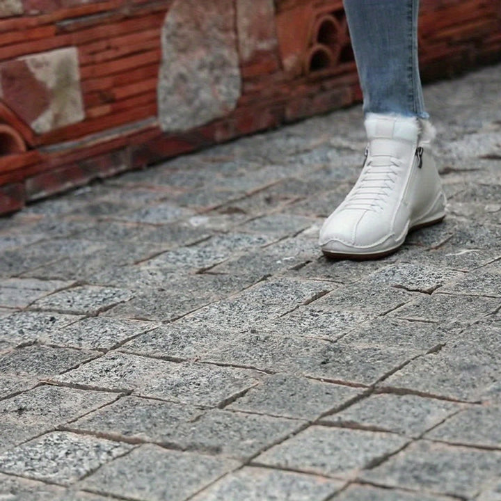 Cremeweiße gefütterte Ankle Boots mit Fellsaum auf gepflastertem Weg getragen