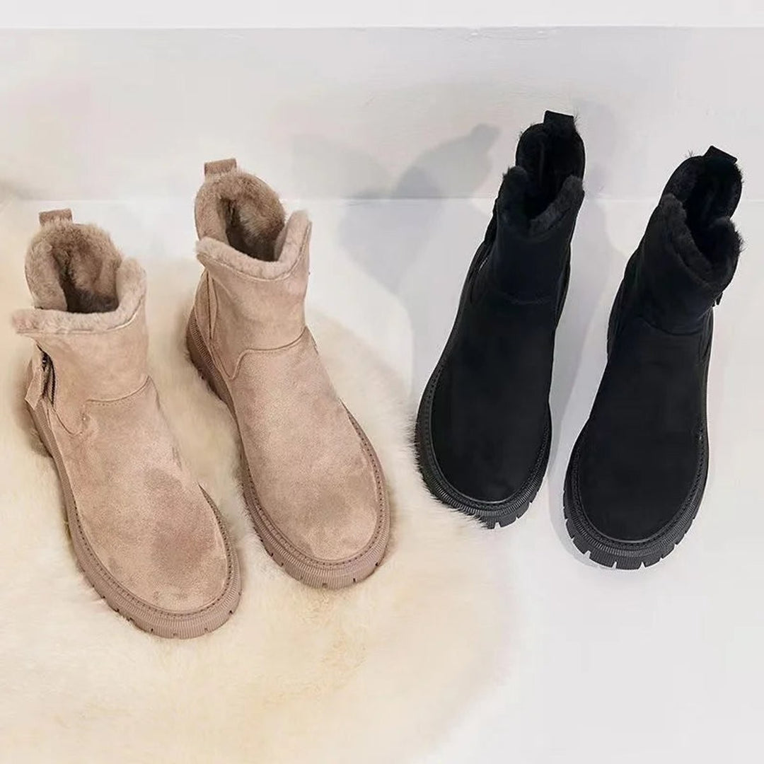 Gefütterte Stiefeletten in Beige und Schwarz nebeneinander auf Fellunterlage