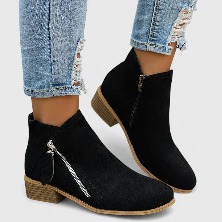 Schwarze Ankle Boots mit seitlichem Reißverschluss vor weißem Hintergrund