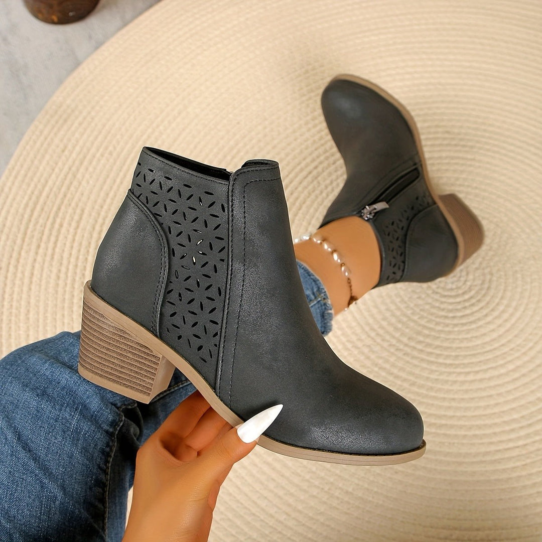 Graue Stiefeletten mit Cut-out-Muster, in der Hand präsentiert