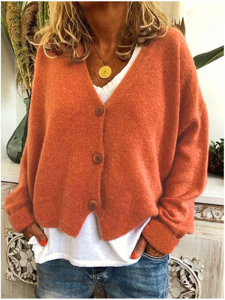 Terracotta-farbene Strickjacke mit V-Ausschnitt und Knopfleiste, kombiniert mit weißem Top