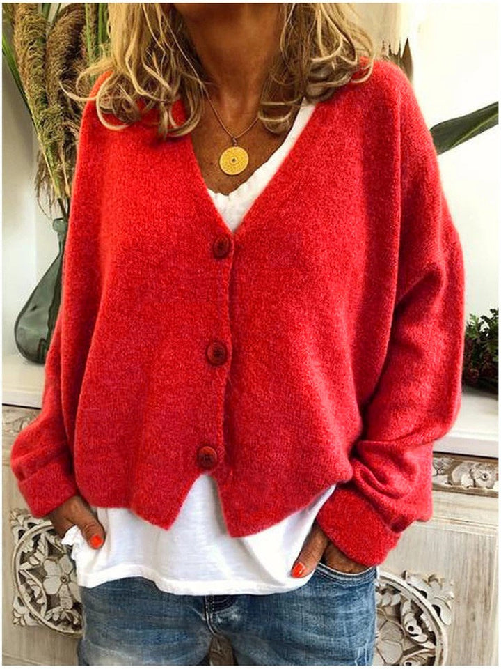 Rote Strickjacke mit V-Ausschnitt und Knopfverschluss über weißem Basic-Top