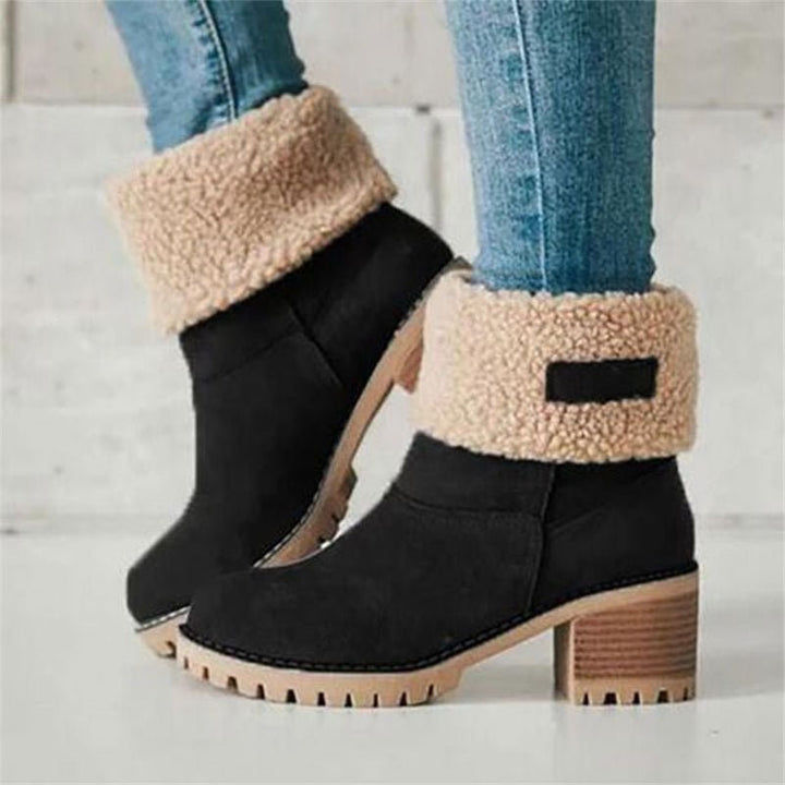 Schwarze Winterstiefel mit Kunstfell-Umschlag und Blockabsatz, am Fuß getragen