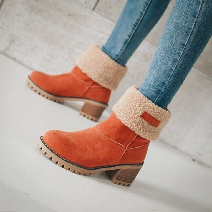 Orangefarbene Winterstiefel mit flauschigem Fellkragen, an den Beinen getragen
