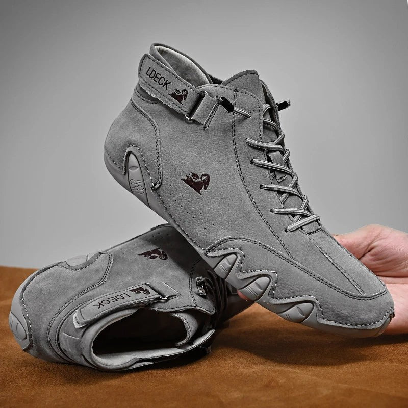 Grauer Wildleder-Barfußschuh mit breiter Passform und Reißverschluss in Hand gehalten