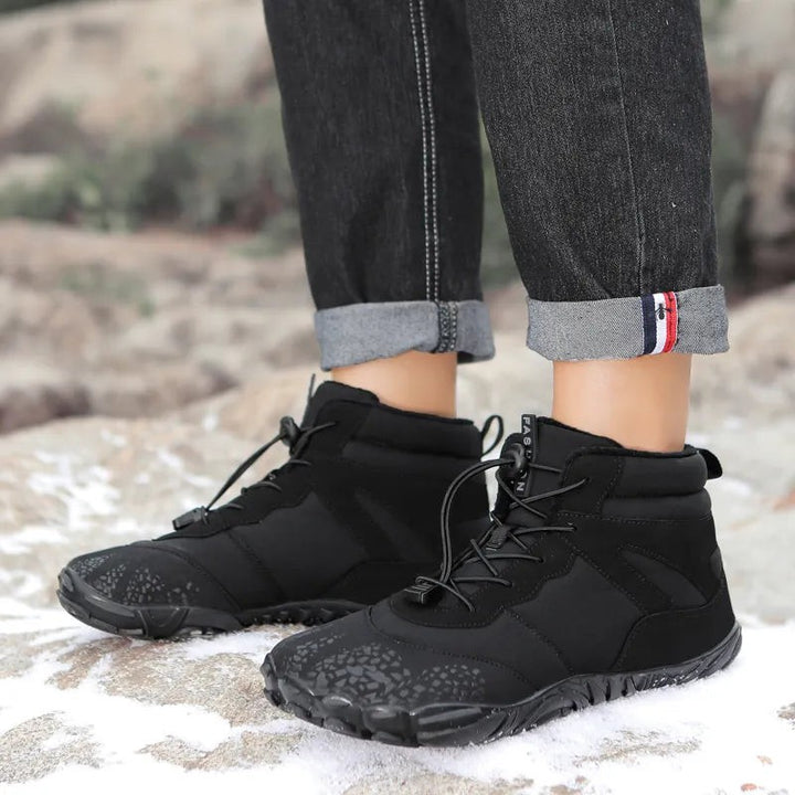 Schwarze Winterboots mit Schnürung im Schnee auf Felsen getragen