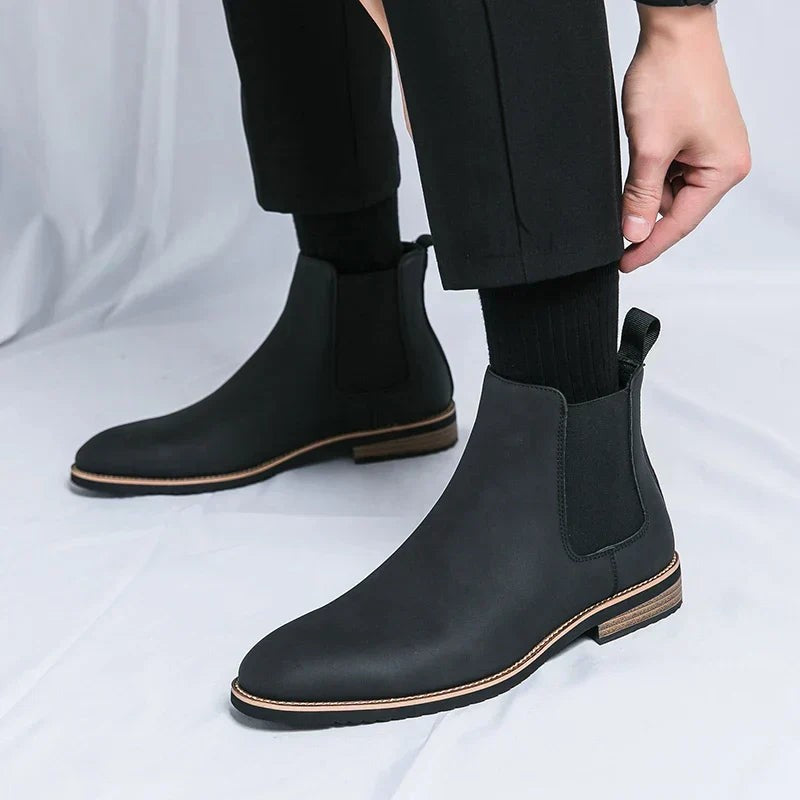 Herren zieht schwarzen Chelsea-Stiefel mit dezenter Kontrastsohle an