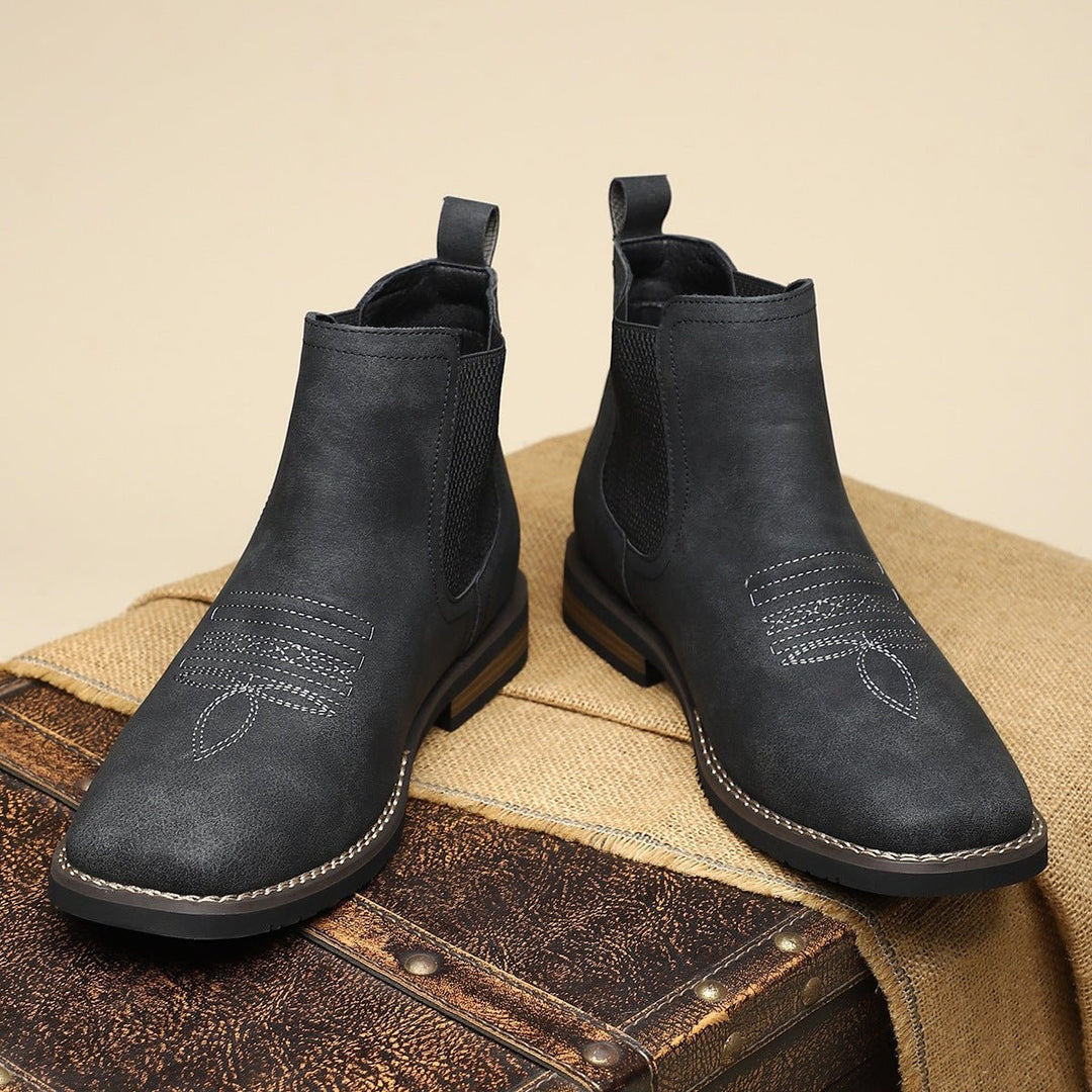 Schwarze Stiefeletten paarweise auf Jute-Stoff mit Vintage-Koffer