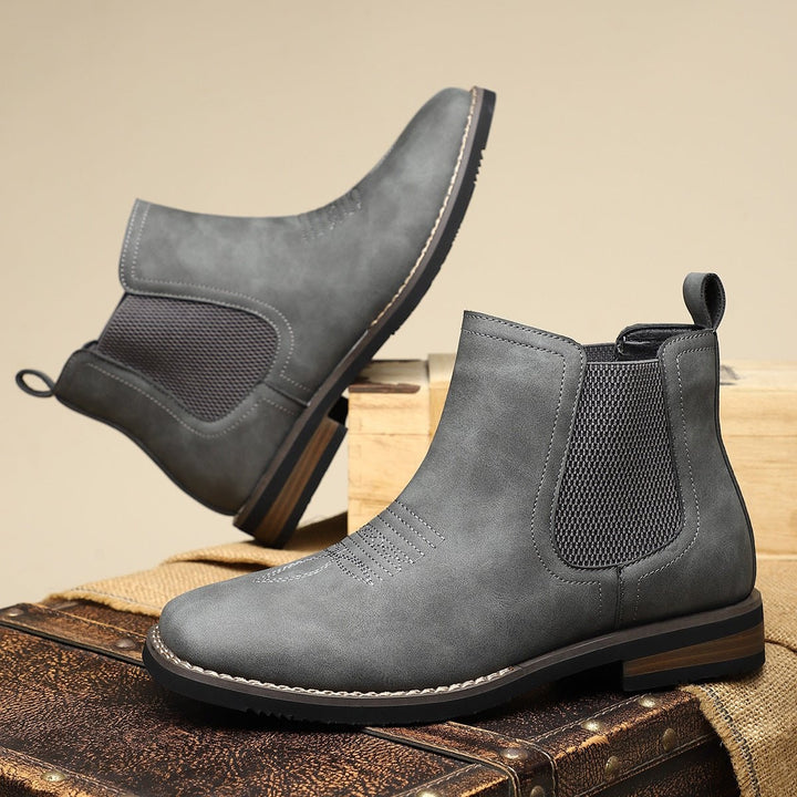 Graue Chelsea Boots im Vintage-Look auf altem Koffer