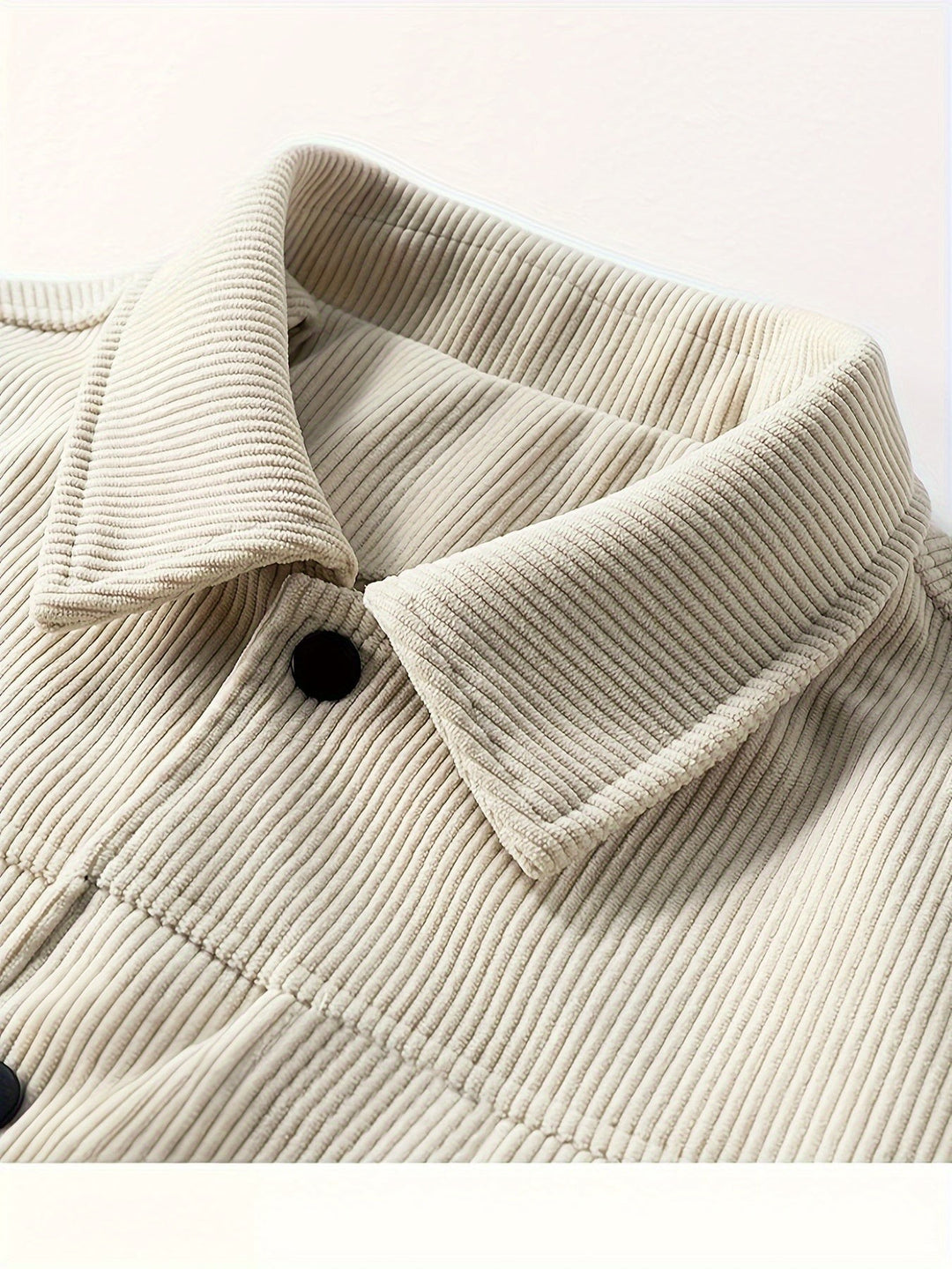 Nahaufnahme des Kragens einer beigen Cord-Hemdjacke mit Druckknopf