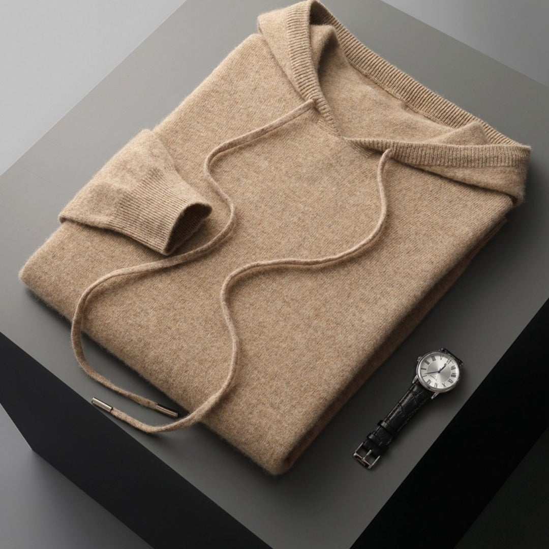Gefalteter Strick-Kapuzenpullover in Beige mit Kordelzug neben Armbanduhr