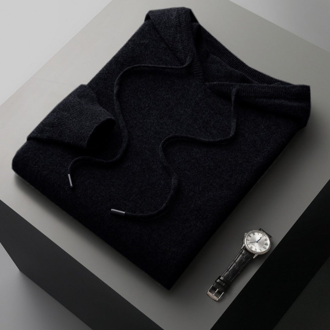 Schwarzer Strickhoodie gefaltet mit Kapuze und Kordelzug neben Uhr