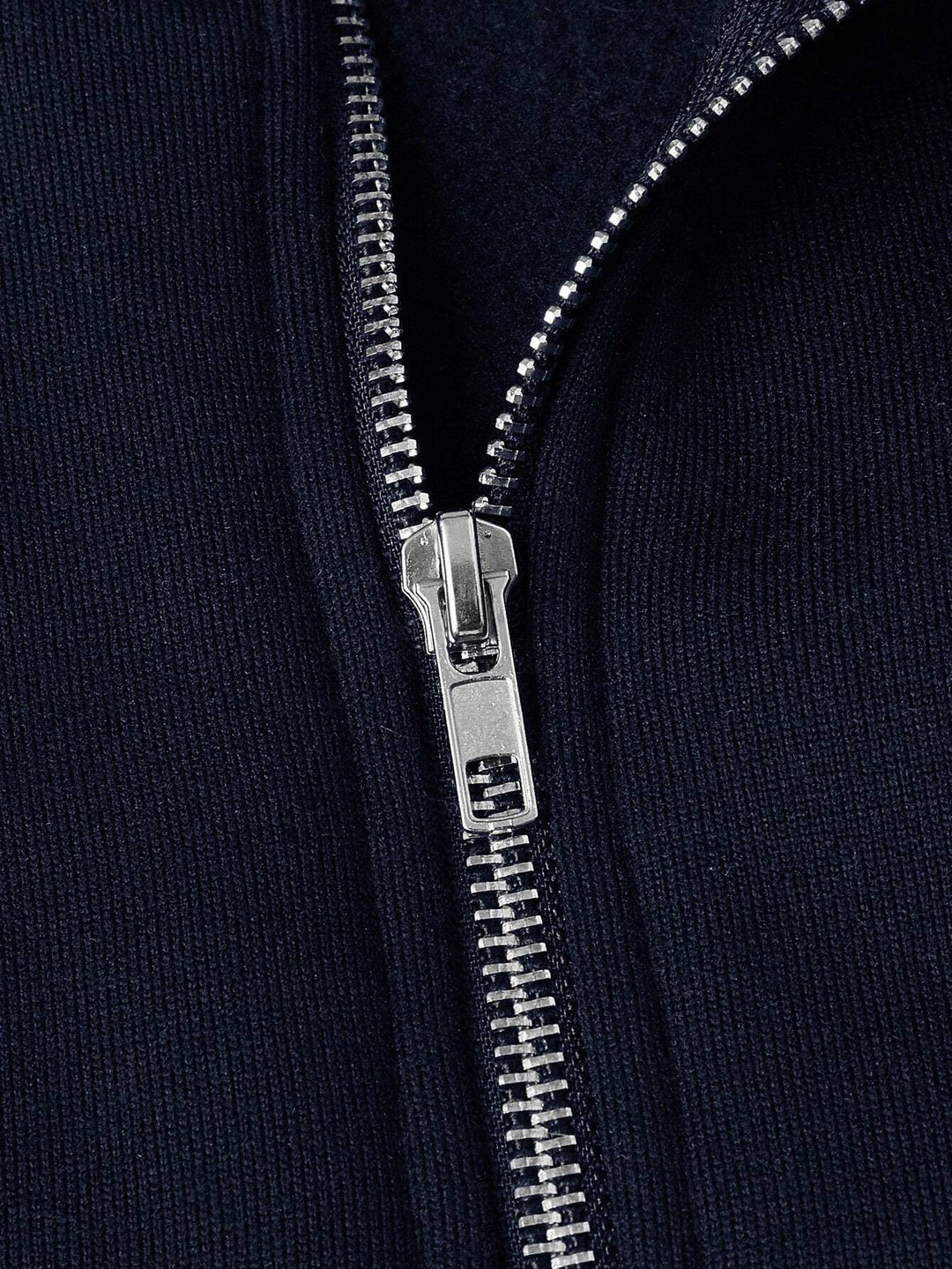Nahaufnahme des silbernen Reißverschlusses am marineblauen Troyerpullover