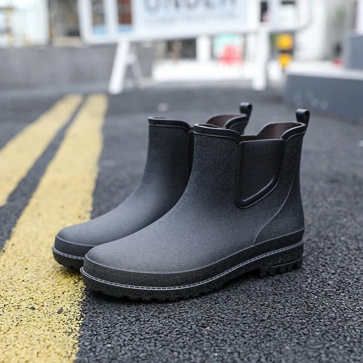Schwarze Chelsea-Regenstiefel mit elastischem Seiteneinsatz auf Asphaltstraße