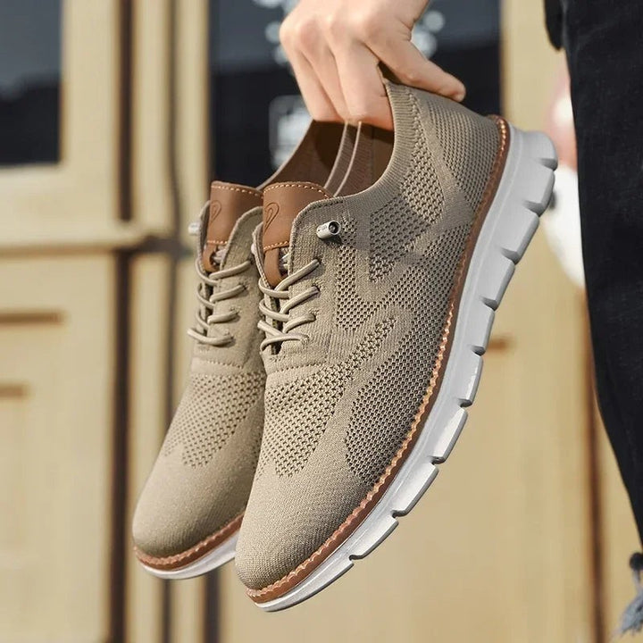 Beige Strick-Sneaker paarweise in der Hand gehalten, weiße Sohle sichtbar