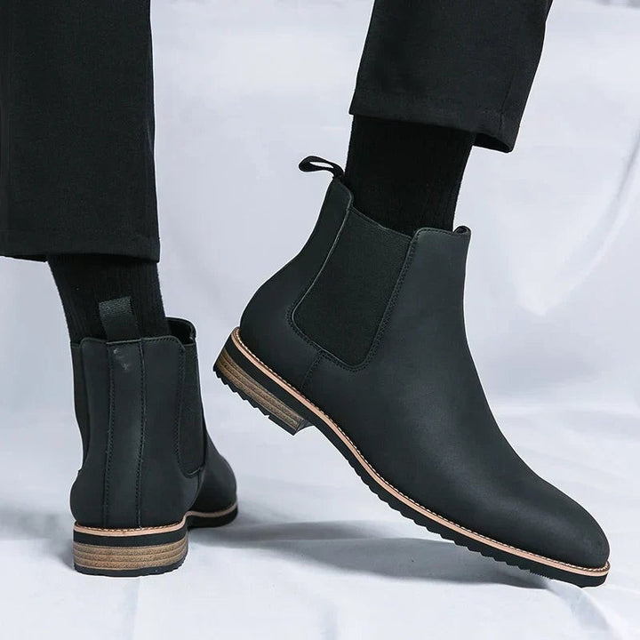 Schwarze Herren Chelsea Boots aus Leder mit elastischem Seiteneinsatz getragen