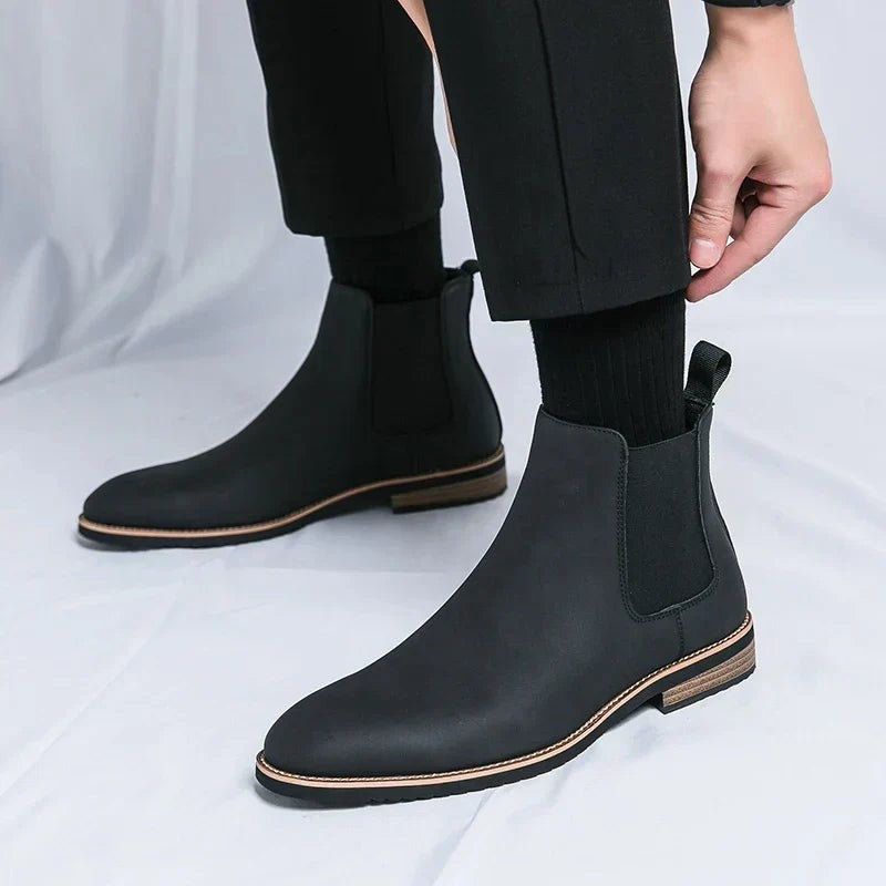 Schwarzer Leder Chelsea Boot mit Zugschlaufe beim Anziehen am Bein