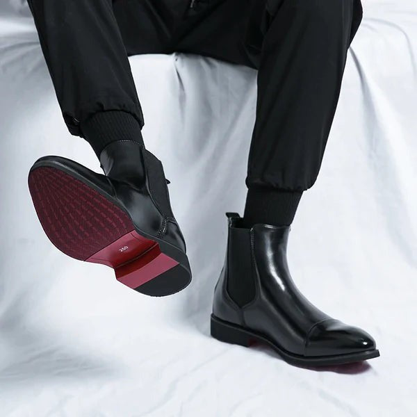 Schwarze Lederstiefel mit roter Sohle beim Anheben des Fußes