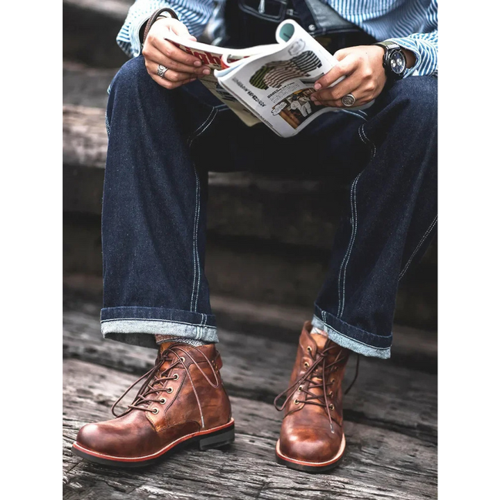 Braune Lederstiefeletten am Fuß in Jeans-Outfit mit Zeitung