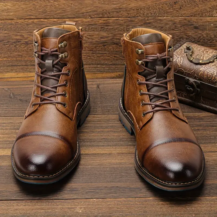Zwei braune Lederstiefeletten mit Schnürung nebeneinander auf Holzboden