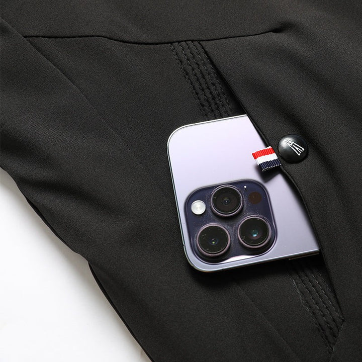 Smartphone in geknöpfter Seitentasche der schwarzen Winterjacke, Detailaufnahme