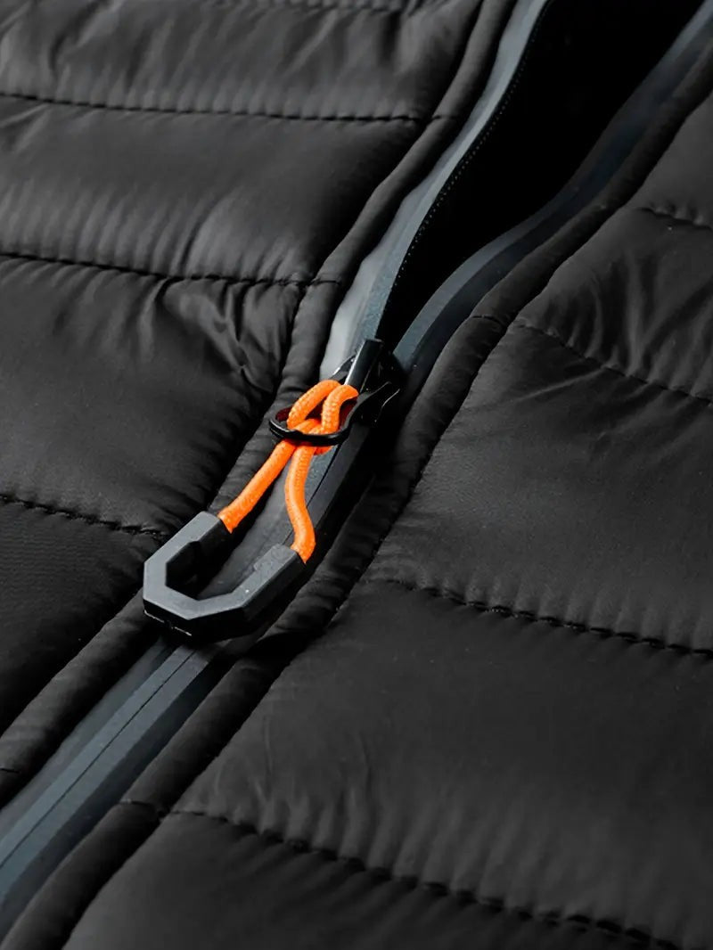 Nahaufnahme des Reißverschlusszugs mit orangefarbener Kordel an Steppjacke