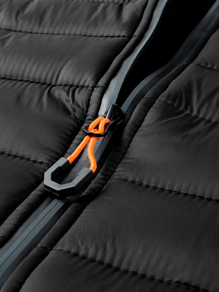 Nahaufnahme des Reißverschlusszugs mit orangefarbener Kordel an Steppjacke