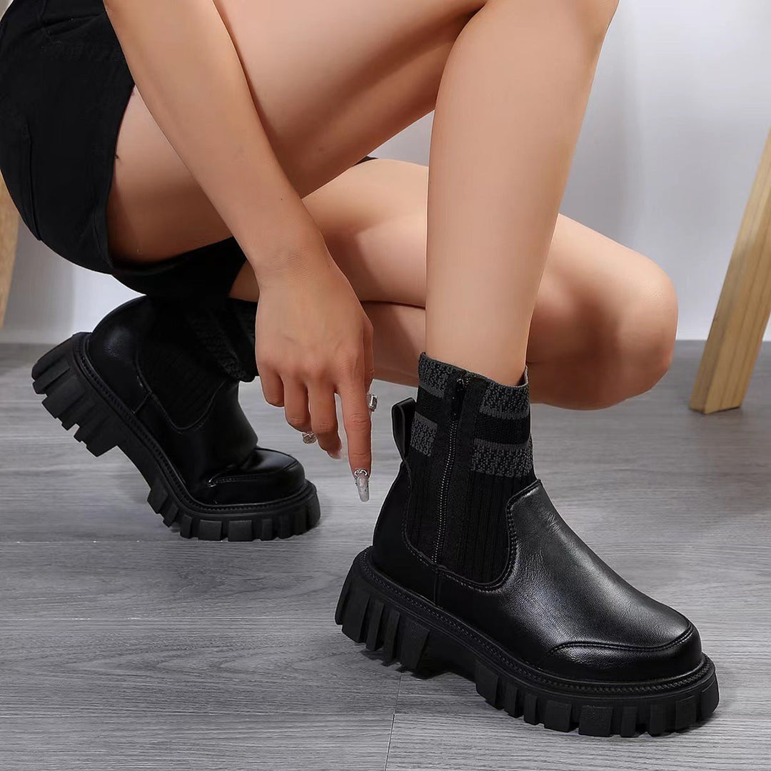 Schwarze Chelsea-Boots mit Strickschaft und dicker Plateausohle, getragen von Frau in Hocke